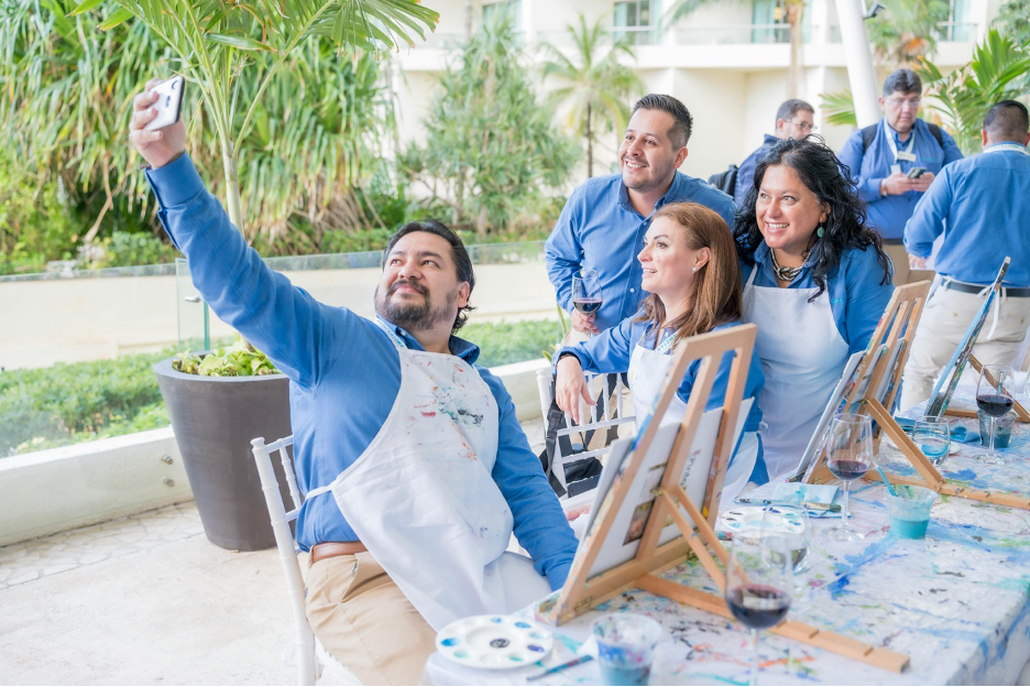 Employees participating in a corporate painting class as part of an employee mental well-being program to reduce stress and support workplace wellness.