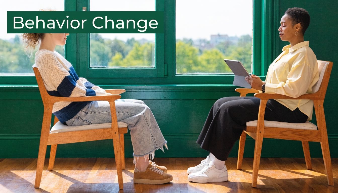 Two women sitting in wooden chairs, facing each other by a window, with 'Behavior Change' text overlay.